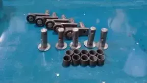 KIT LEVAS IF 1550 6 Kit de tornillos, pernos y arandelas metálicas organizados sobre superficie azul, componentes de fijación y sujeción para ensamblaje mecánico