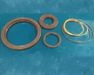 KIT DE RETENES Y O´RING/ Implecor 4 Conjunto de juntas y sellos de goma de diferentes tamaños y colores dispuestos sobre superficie azul, incluyendo anillos tóricos y arandelas de sellado para maquinaria